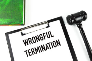 Green book, judge gavel and white paper written with WRONGFUL TERMINATION