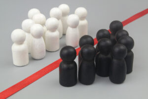 Groups of white and black people figures separated by red line on gray background. Racial separation concept.