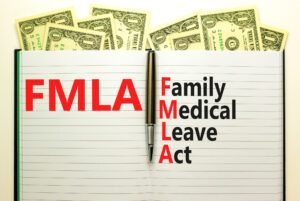 FMLA family medical leave act symbol. Concept words FMLA family medical leave act on book on beautiful white background. Dollar bills. Medical FMLA family medical leave act concept.